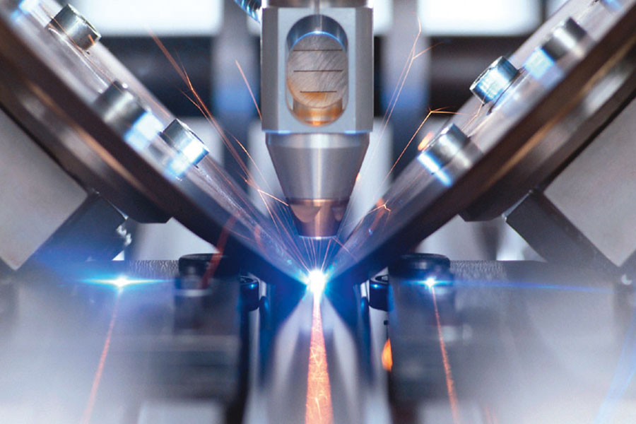 Ausschnitt eines Laserkopfes mit blau, orange, violetten Funken beim Laserschweißen